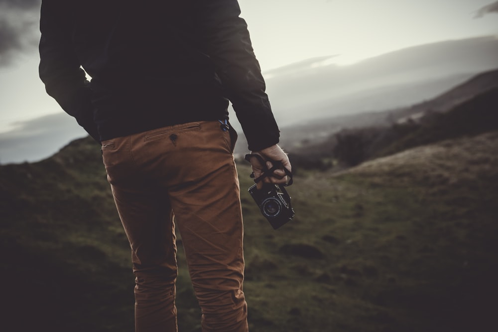 man standing uphill holding black digital camera