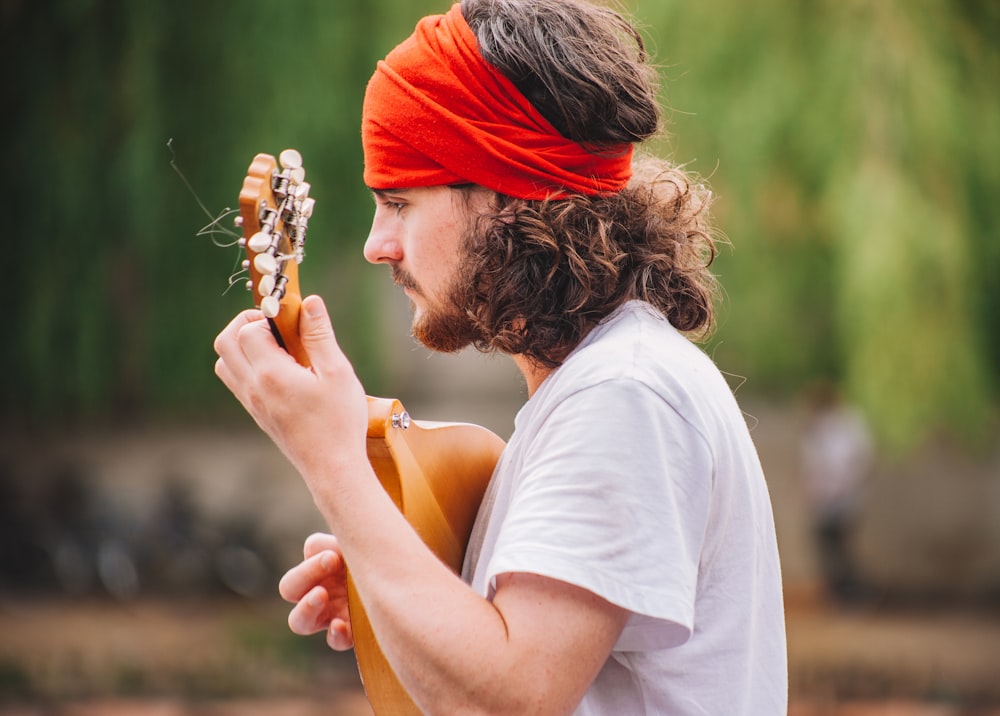 shallow focus photography of man playing guitar outdoors