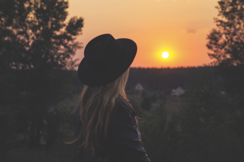 woman wearing black hat staring at sunset