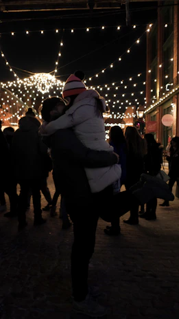 A silhouette of a couple sharing a laugh under warm string lights in a private outdoor space.