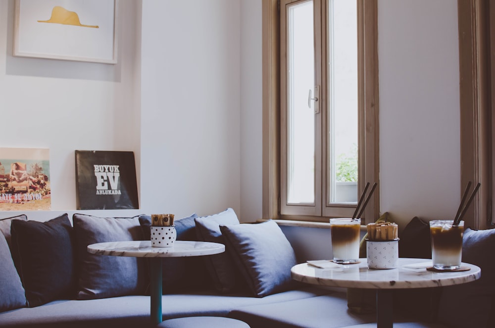 two round wooden framed tables near gray padded sofa