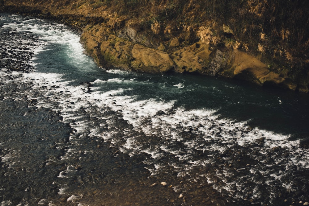 Specchio d'acqua con scogliera accanto durante il giorno