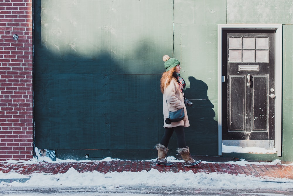 woman standing beside wall and door during daytime