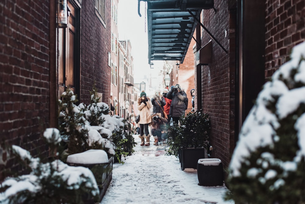 chica de pie entre edificios rodeada de plantas cubiertas de nieve