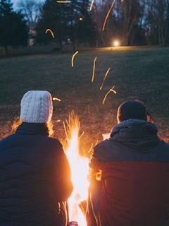 Couples relaxing by a bonfire near a charming farmhouse in the cool evening.