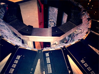 A circular structure made up of segments with numerous cables and wires visible around the perimeter. The structure appears metallic with dark panels and hardware details, suggesting it could be part of an electronic or mechanical apparatus.