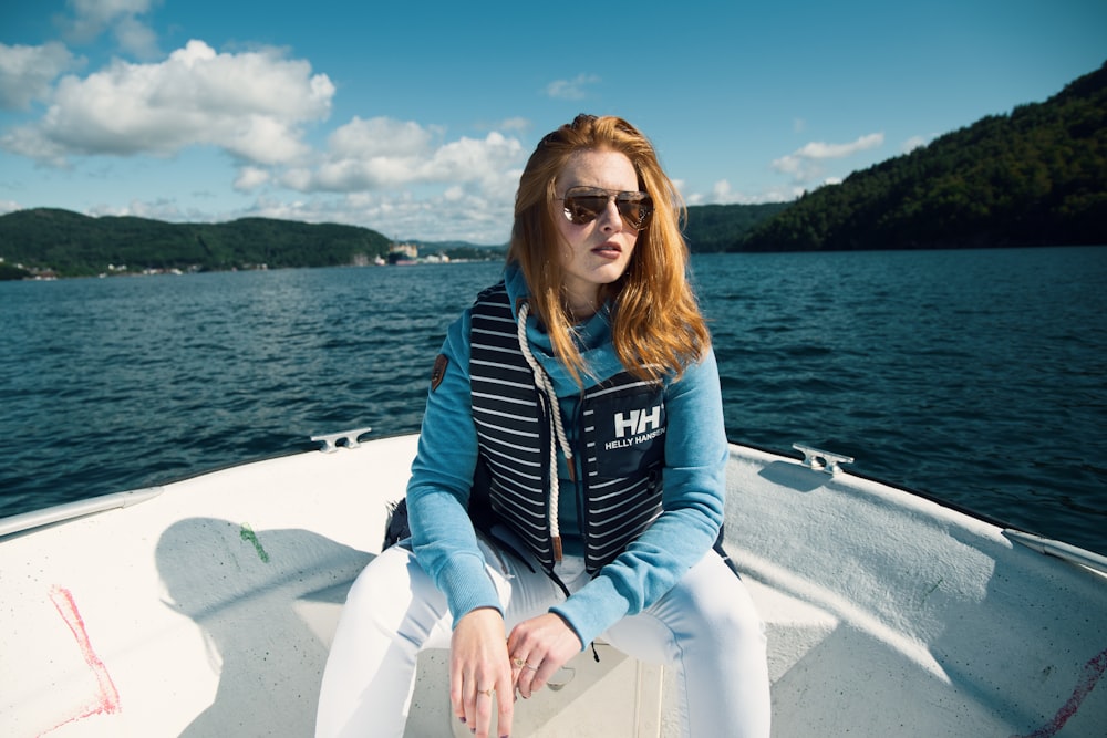 femme assise sur un bateau près de la montagne pendant la journée