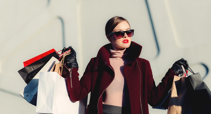 photo of woman holding white and black paper bags