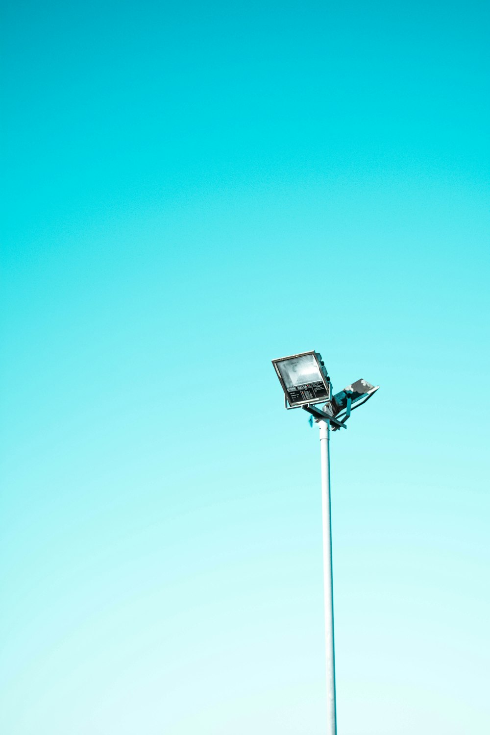 poste de luz branca e preta sob o céu azul