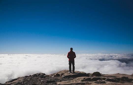 man standing on brown mountains facing sea of clouds in Torrecilla Spain
