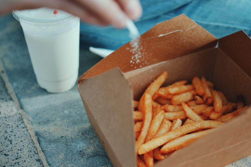 Person, die Salz in Pommes frites streut