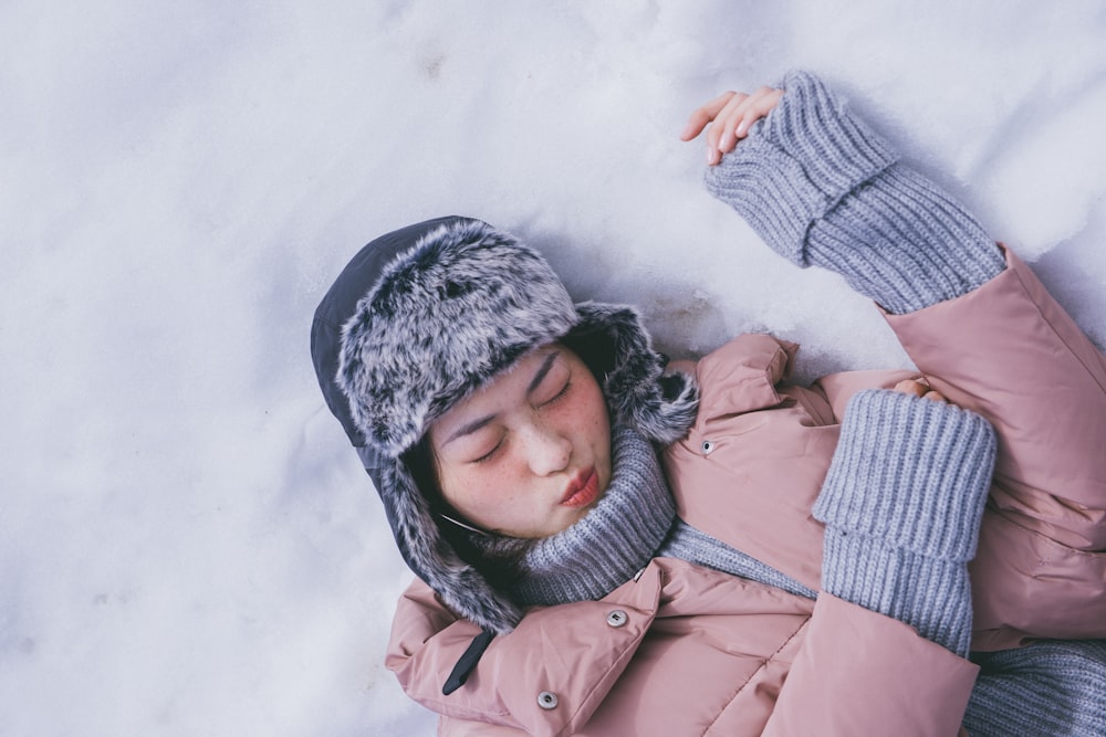 woman lying on white snow during daytime