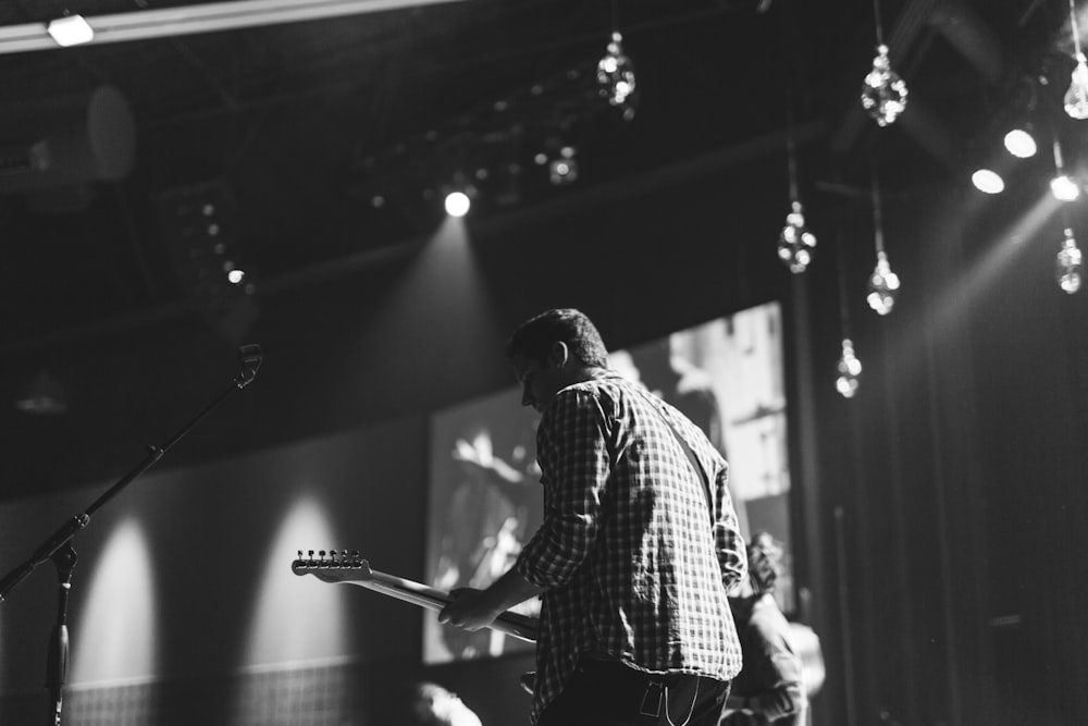 grayscale photo of man playing electric guitar