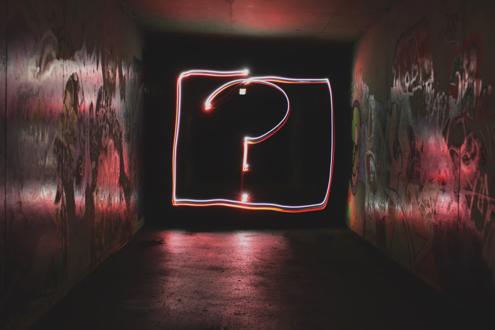 A glowing neon question mark sign in a dark tunnel