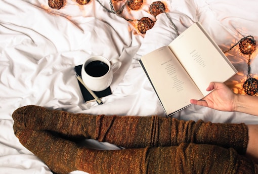mug of black coffee beside person's feet wearing brown stockigns