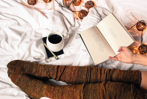 mug of black coffee beside person's feet wearing brown stockigns