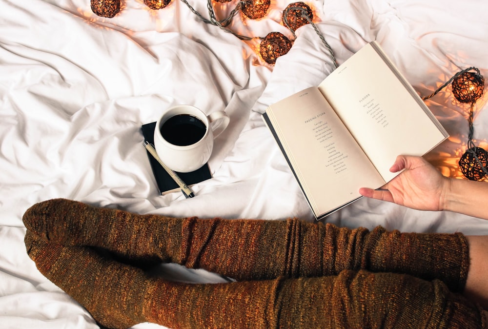 mug of black coffee beside person's feet wearing brown stockigns