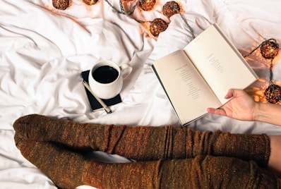 mug of black coffee beside person's feet wearing brown stockigns