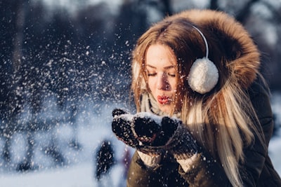 woman blowing snow on her hands mittens google meet background