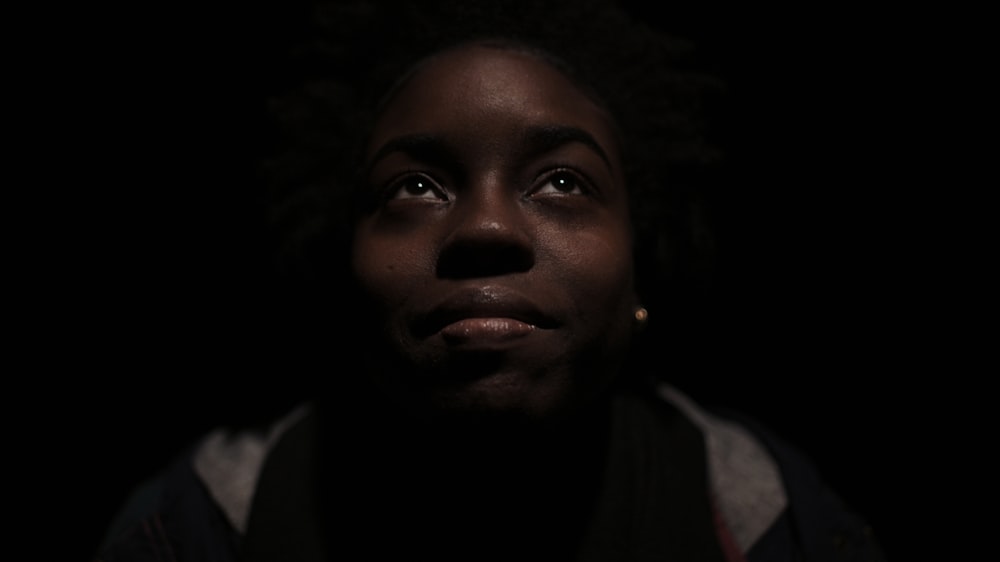 woman in gray and black shirt surrounded with darkness