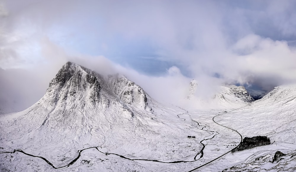 fotografía de paisaje de montaña cubierta de nieve bajo cielo nublado