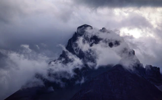 A misty mountain peak at dawn, captured with cinematic lighting and deep shadows.