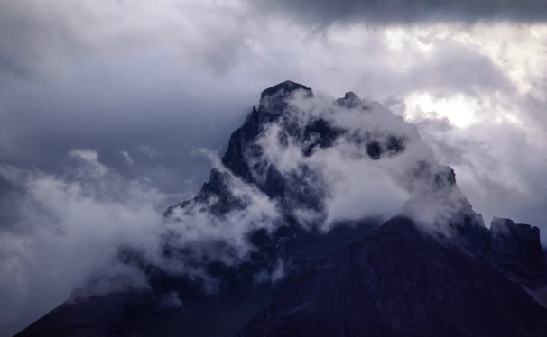 A misty mountain peak at dawn, captured with cinematic lighting and deep shadows.