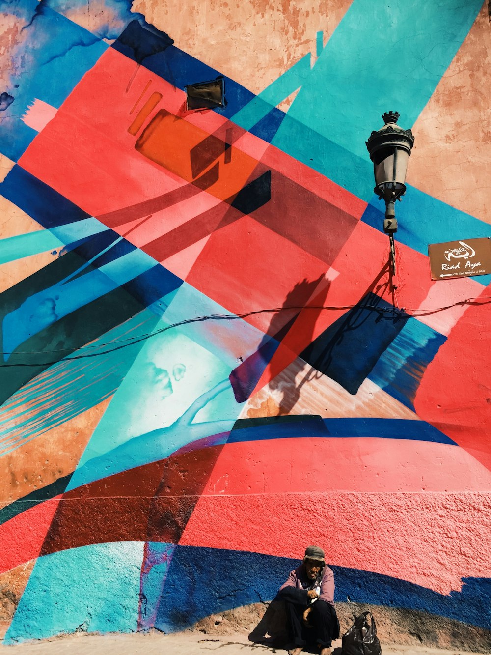 man sitting on wall with artwork and lamp