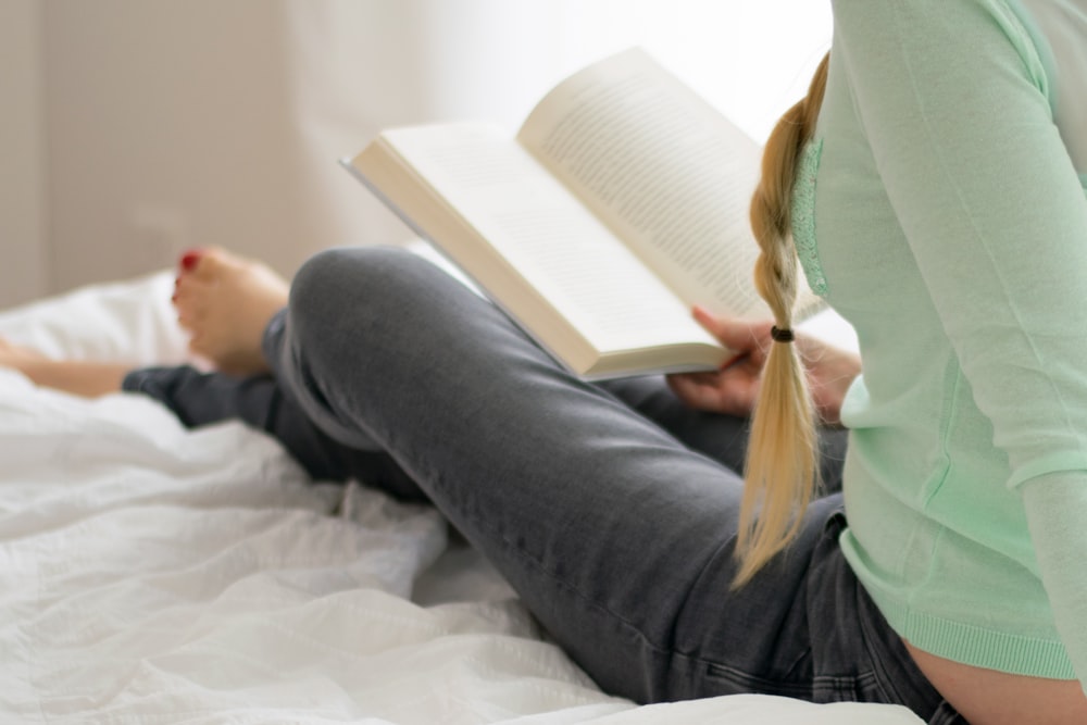 a woman laying on a bed reading a book