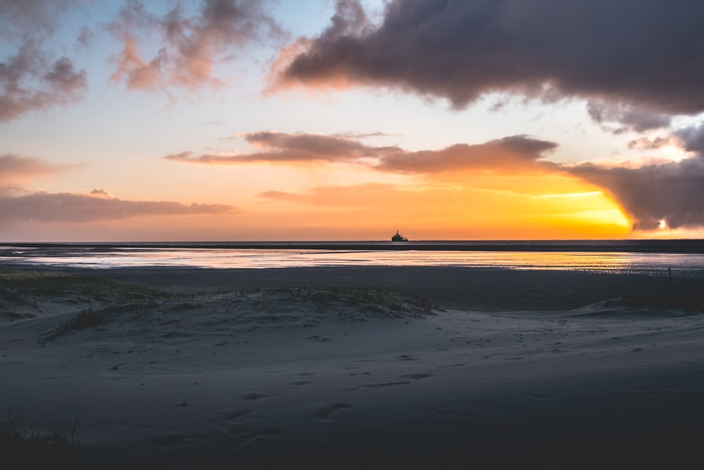 body of water under cloudy sky during sunset