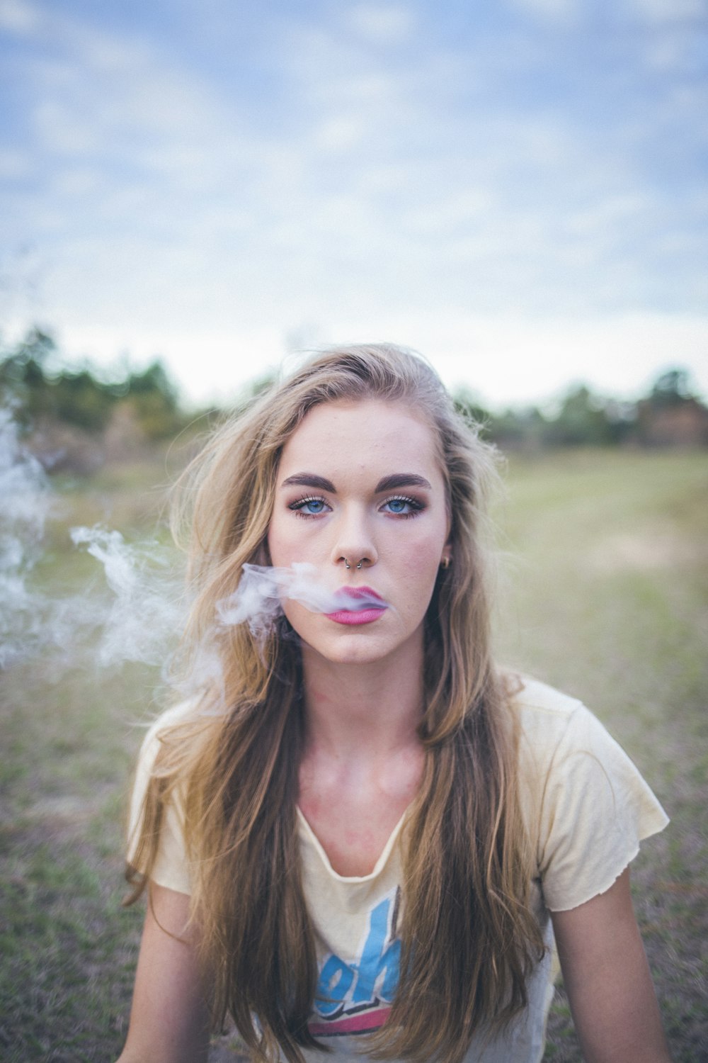 緑の芝生に座ってタバコを吸う女性