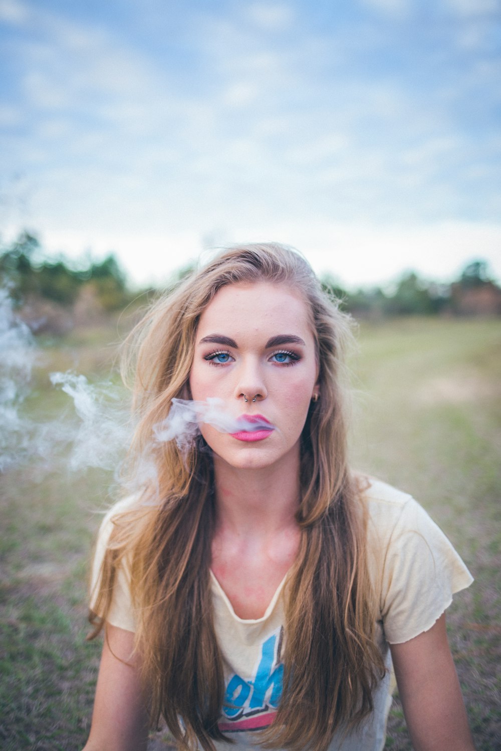 woman smoking while sitting on green grass