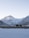 A majestic snow-covered mountain range with a prominent peak under a clear sky. The foreground features grazing yaks on a rocky, snow-dusted plain.