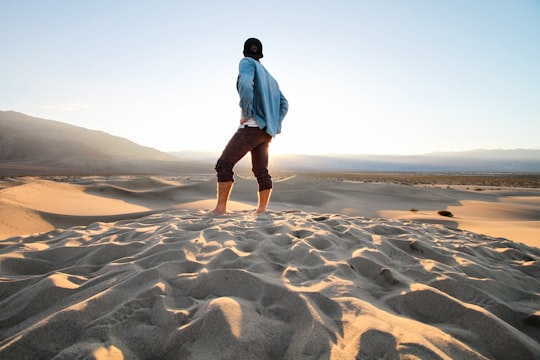 person standing at sand wearing black pants and teal jacket in Death Valley National Park United States