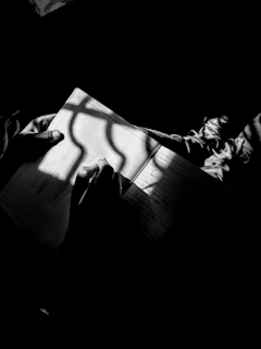 A close-up of a young writer’s hands sketching story ideas in a notebook with warm sunlight filtering through a window