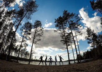A joyful group of people singing together outdoors on a sunny summer day.