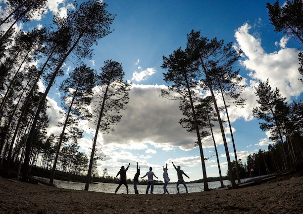 A joyful group of people singing together outdoors on a sunny summer day.