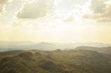 Bird's-eye view of rolling hills with patchwork farmland in golden light.