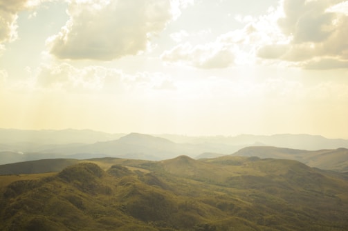 Bird's-eye view of rolling hills with patchwork farmland in golden light.