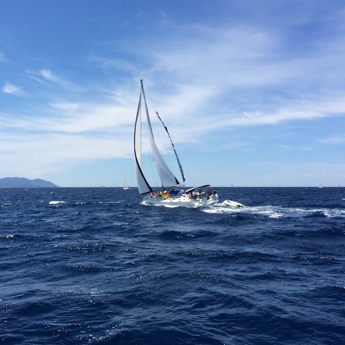 A sailboat sailing on blue water in winter sunshine