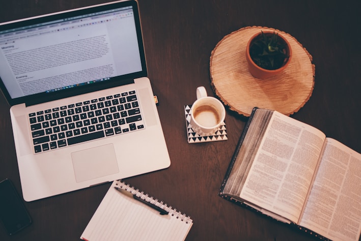 A cozy workspace with an open e-book on a tablet surrounded by notes and a cup of coffee