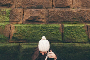 A cozy knitted beanie in warm earth tones displayed against a rustic brick wall.