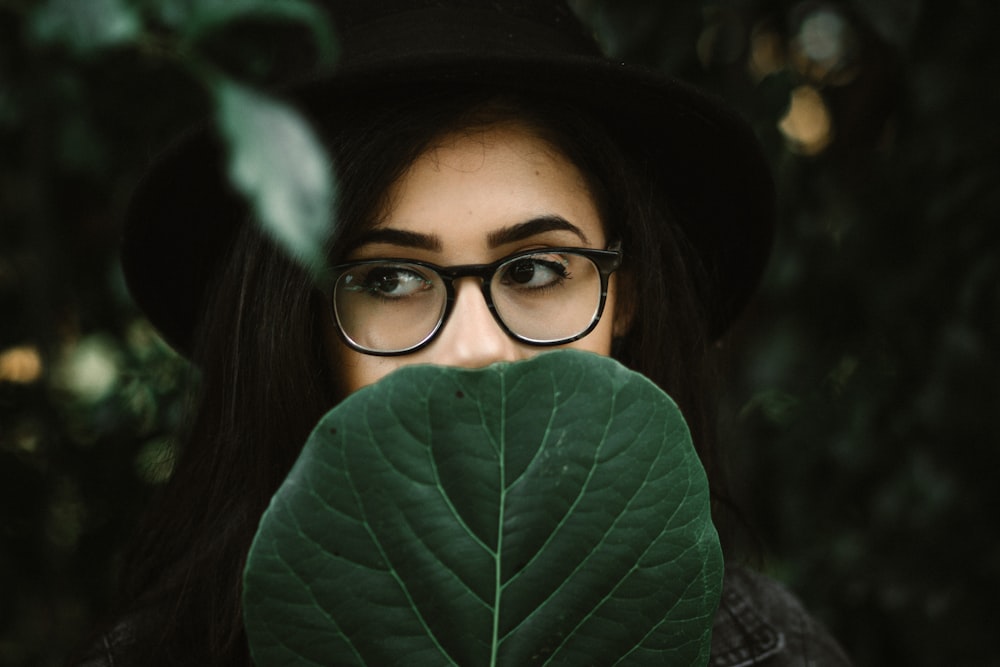 mujer cubriéndose la boca con una hoja verde