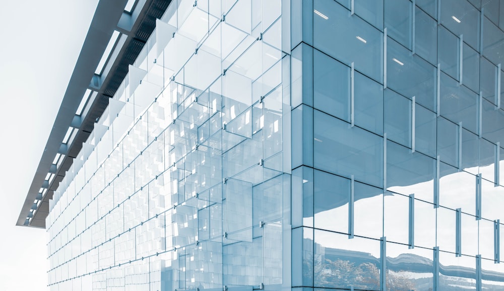 architectural structure photography of glass building under cloudy sky