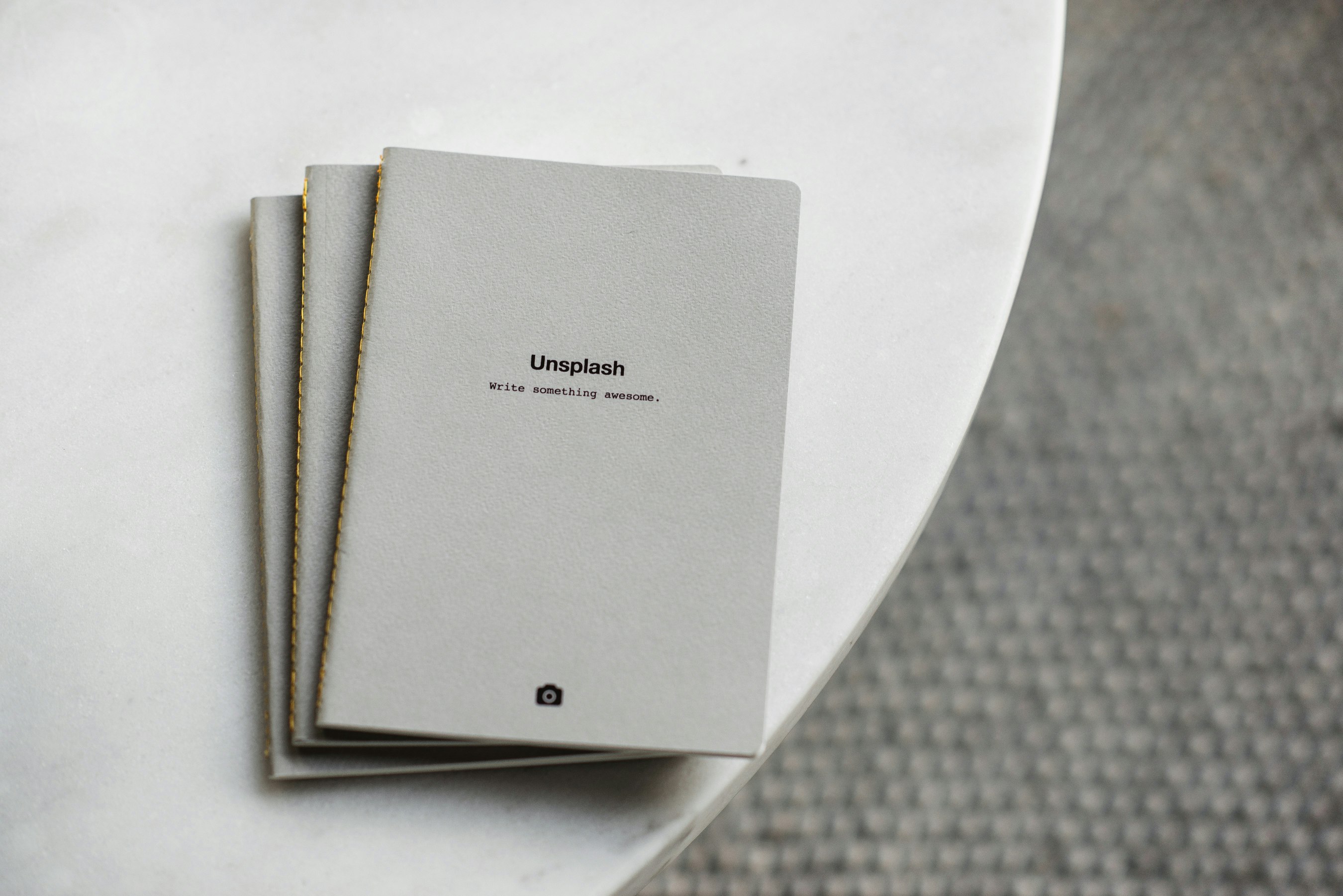 three white softbound books on white surface