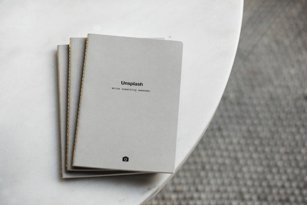 three white softbound books on white surface