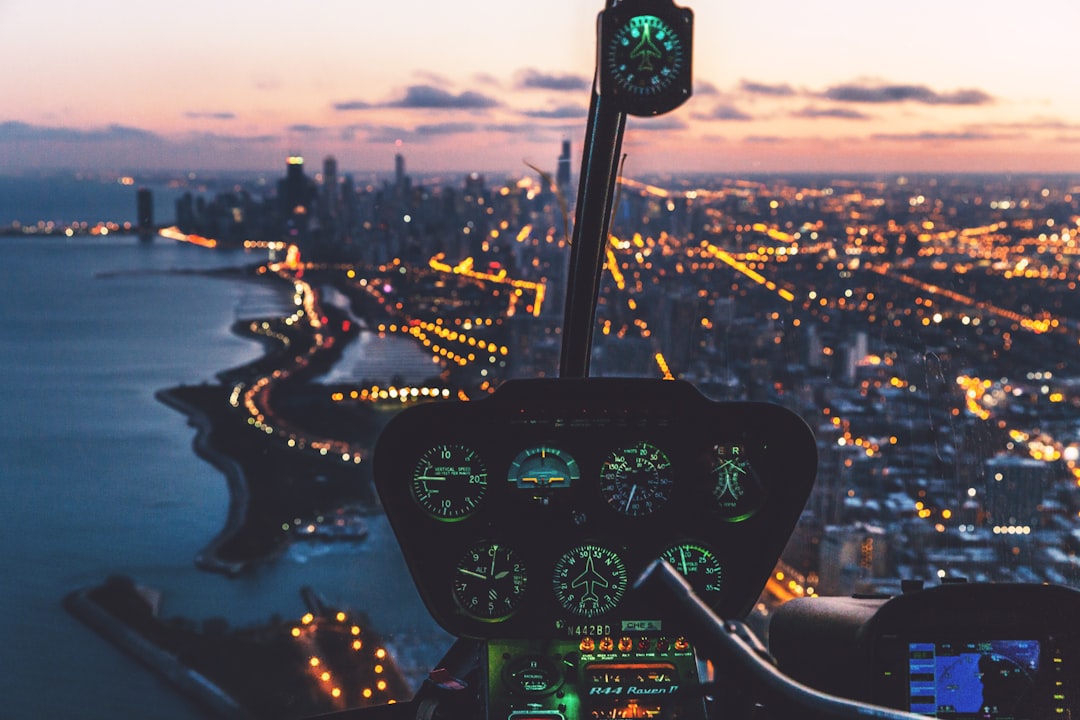 aerial view photography of helicopter cockpit and cityscape by water, Helicopter and city at dusk