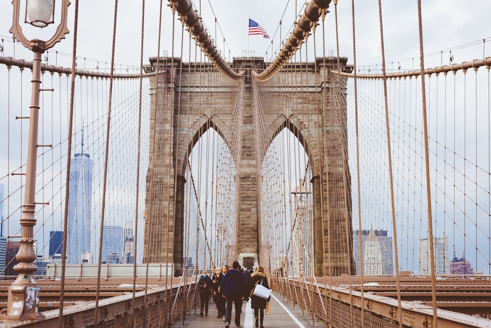 personas caminando por el puente de Brooklyn durante el día