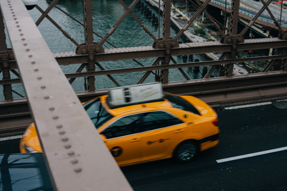 yellow sedan crossing bridge