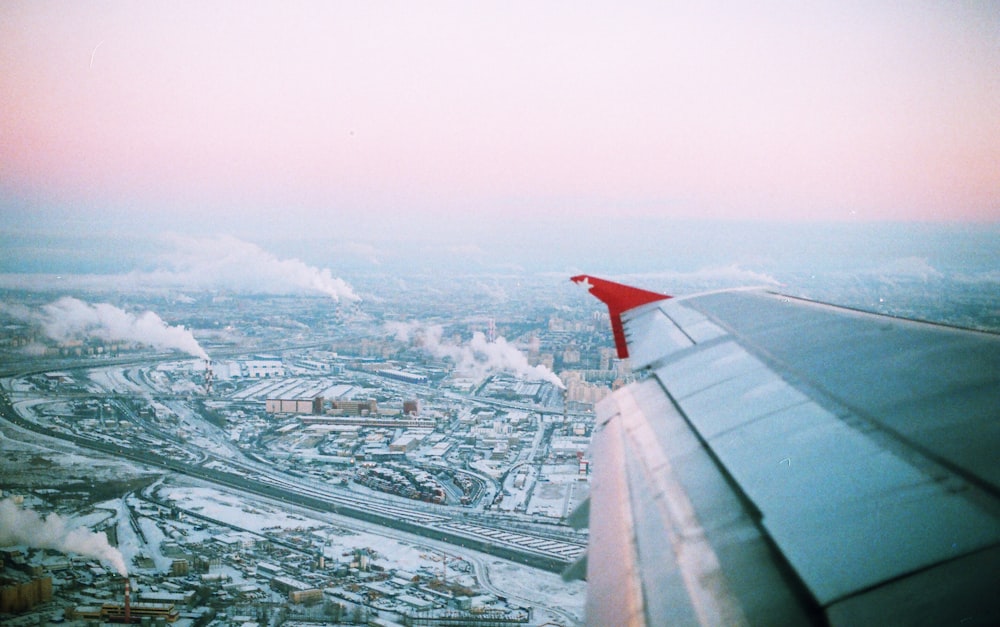 photo of flying airplane wing and city during daytime